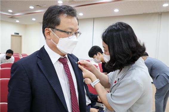 김중식 서울에너지공사 사장(왼쪽)에게 서울사회복지공동모금회 관계자(오른쪽)가 사랑의 열매를 달아주고 있다. (사진=서울에너지공사 제공)