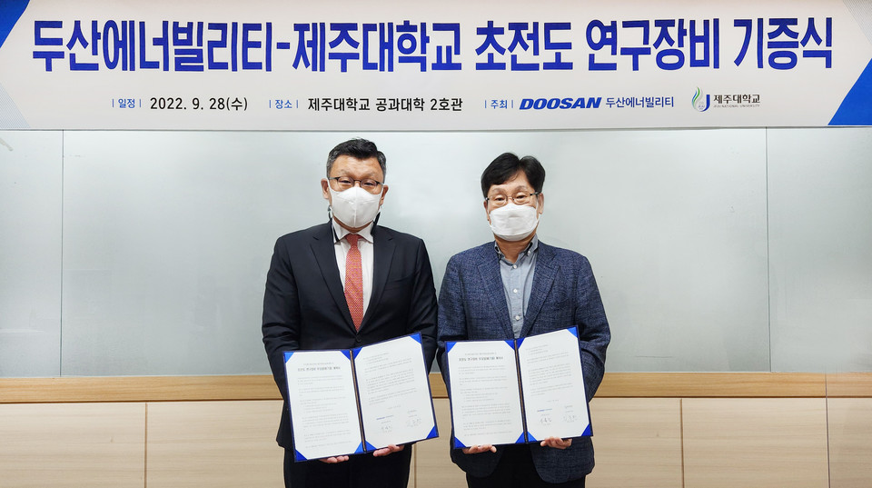 28일 제주대학교에서 열린 ‘두산에너빌리티-제주대학교 초전도 연구장비 기증식’에 참석한 제주대 공과대학 학장인 임종환 교수(오른쪽)와 두산에너빌리티 전략혁신부문 송용진 부사장(왼쪽)이 서명 후 기념촬영을 하고 있다. (사진=두산에너빌리티 제공)