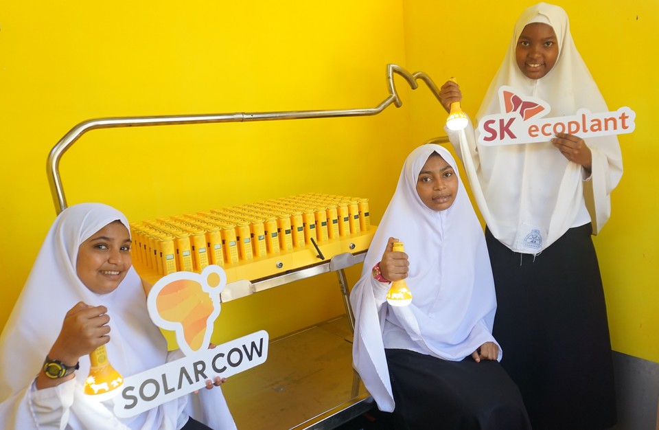 학생들이 설치된 솔라카우 앞에서 충전된 솔라밀크를 들고 웃고 있는 모습. (사진=SK에코플랜트 제공)